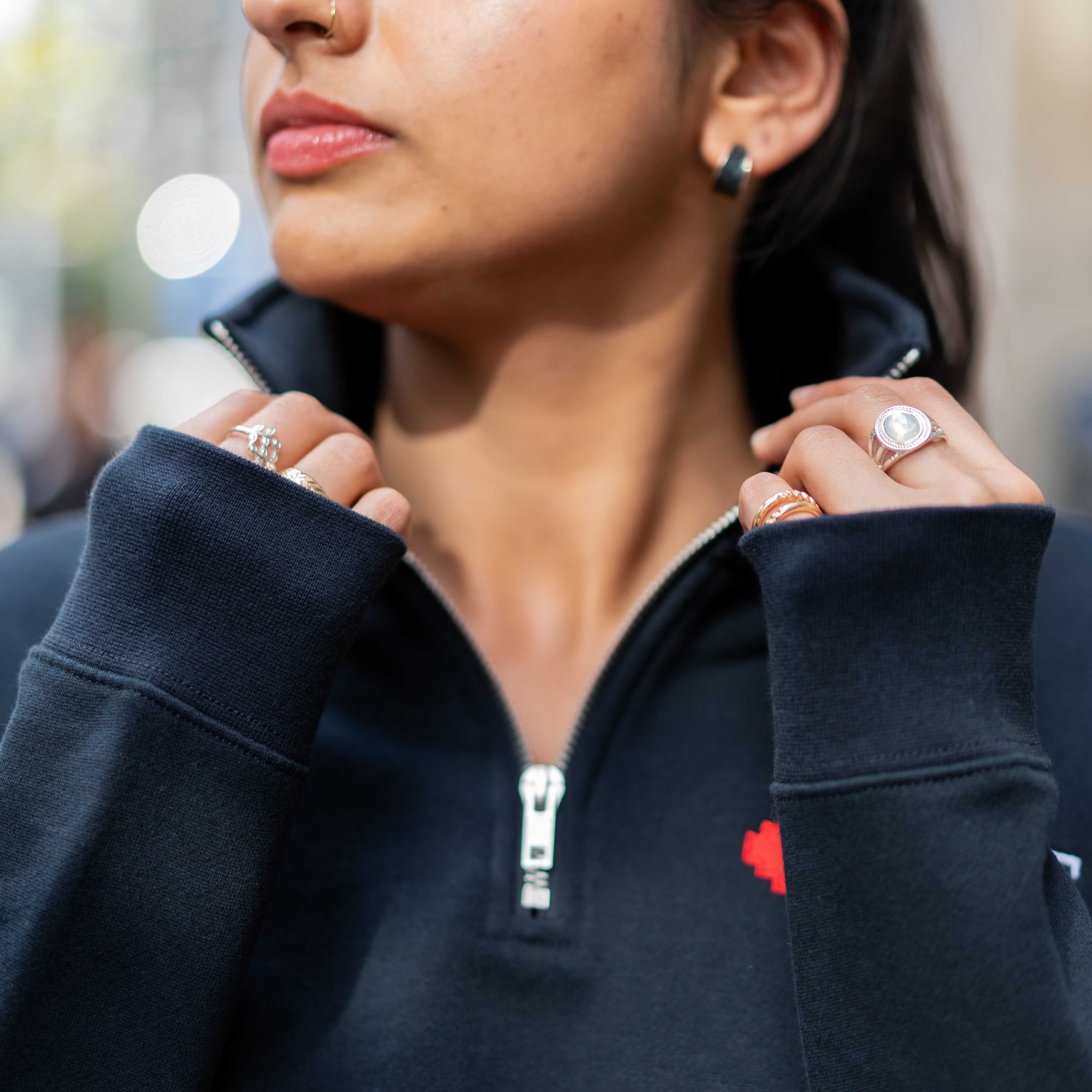 Close-up of student adjusting collar on RMIT Essential half zip jumper in navy with embroidered RMIT University logo.