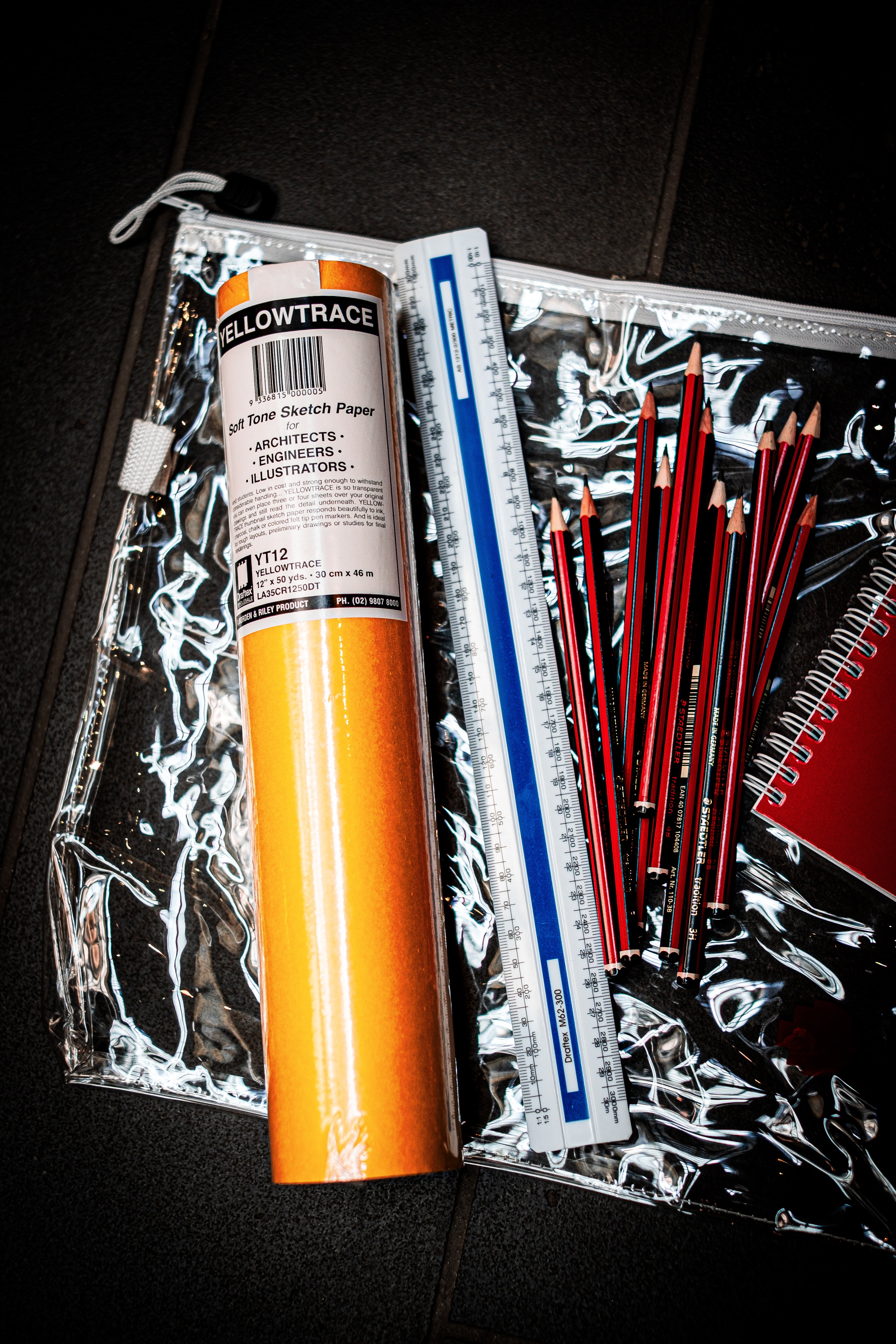 Contents of RMIT Store's Interior Design and Decoration Kit displayed, including Yellowtrace sketch paper, scale ruler, RMIT A5 visual diary, and an assortment of pencils in a clear pouch.