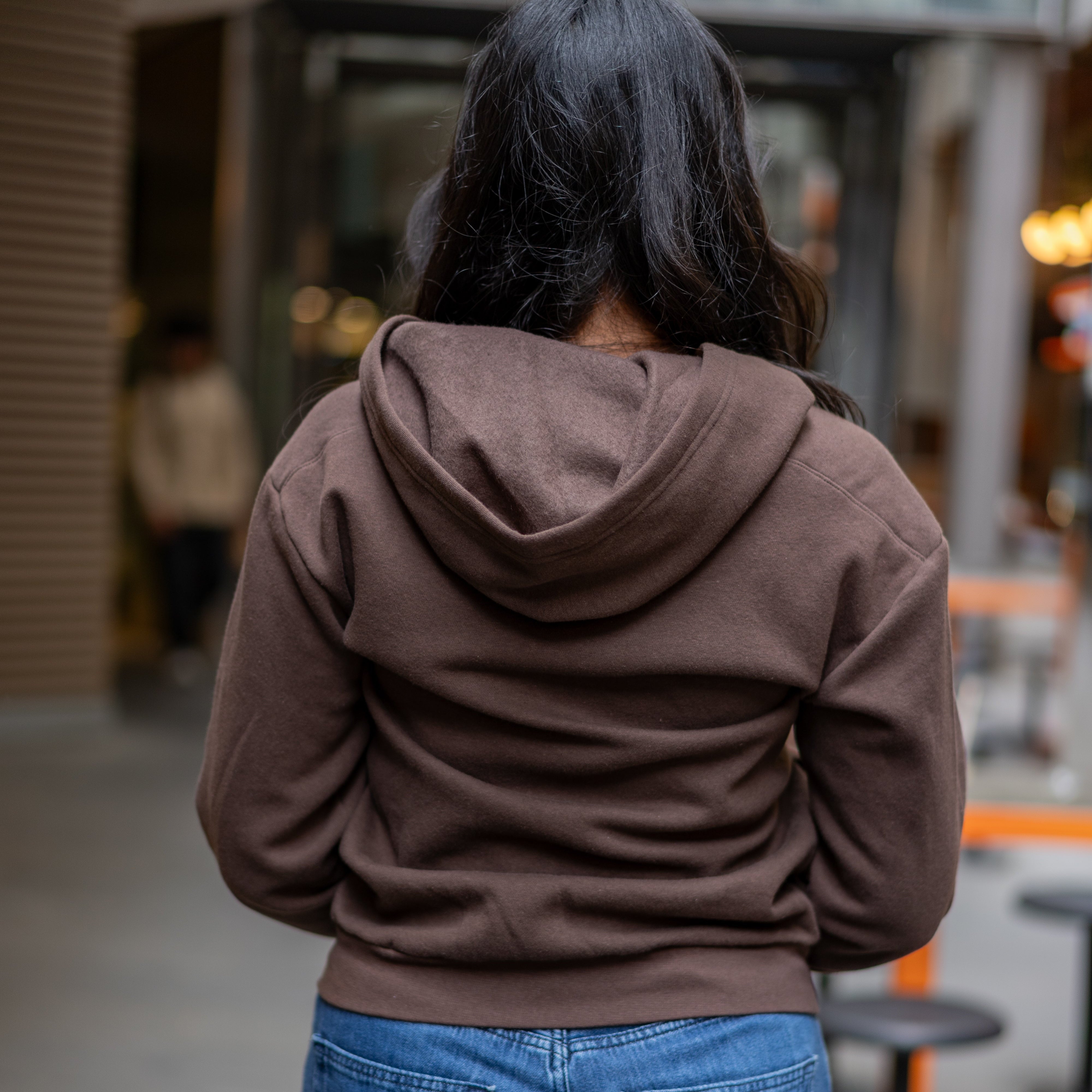 Back view of student wearing RMIT University zip jacket in chocolate brown on campus.