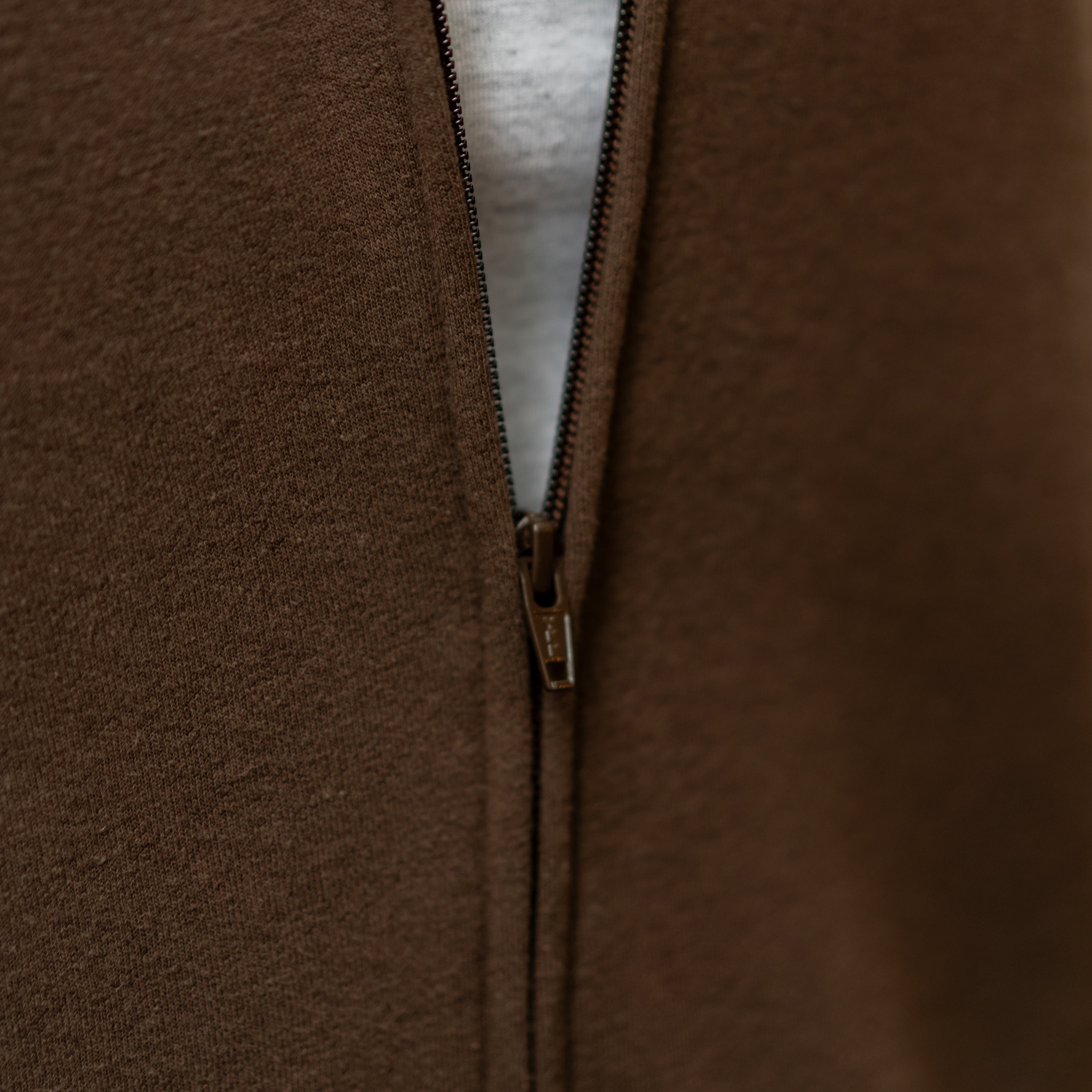 Close-up of zipper detail on RMIT University zip jacket in chocolate brown.